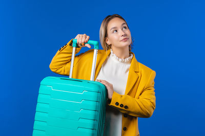 Low angle view of young woman standing against blue sky