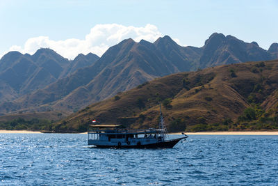 Boat sailing on sea against mountains