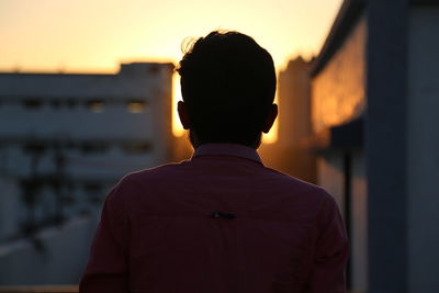 Rear view of man standing against sky during sunset