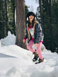 Cheerful girl walking in forest during winter
