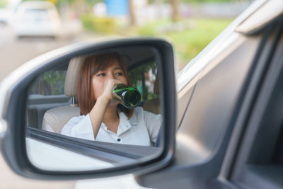 Portrait of woman photographing through car