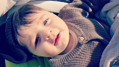 Close-up portrait of baby boy relaxing in stroller on sunny day