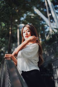 Young woman looking away while standing on tree