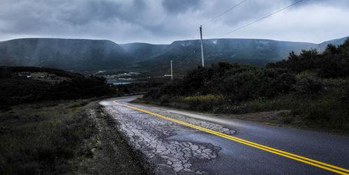 Road leading towards mountain against sky