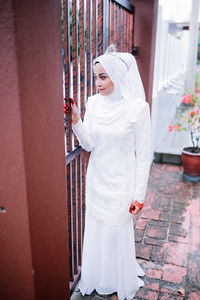 Smiling young woman standing by gate