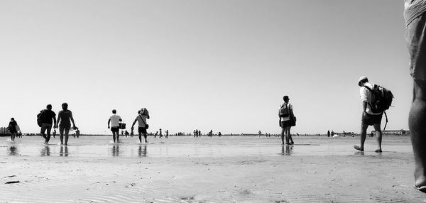 People on beach against clear sky