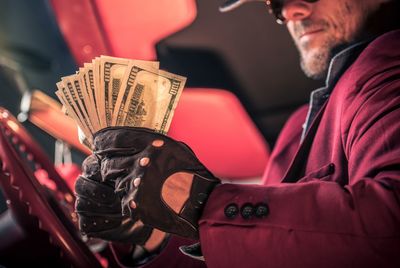 Midsection of man holding paper currencies