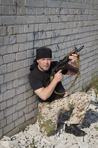 Man holding camera against wall