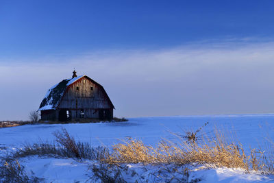 Abandoned building on field against sky during winter