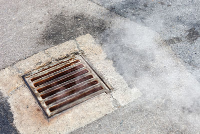 High angle view of metal grate on road