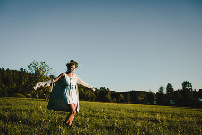 Woman dancing on a field against clear sky.