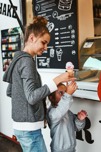 Teenage girl and her younger sister buying ice cream in a food truck during summer vacations