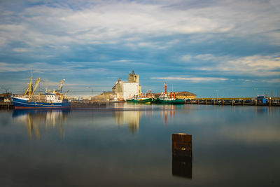 Boats moored in sea against cloudy sky