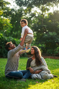 Family with a child sitting on grass in a park