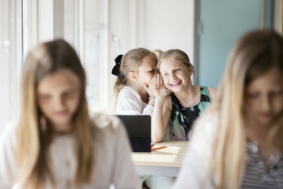 Happy girls whispering in classroom