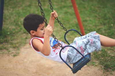 Side view of boy on swing in park