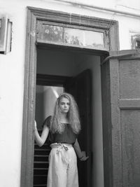 Portrait of young woman standing against door