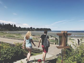 Rear view of women standing by sea against sky