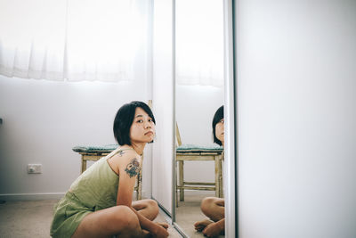 Portrait of young woman looking through window