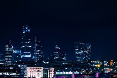 Illuminated buildings in city against sky at night