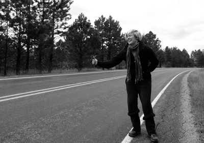 Full length of woman showing thumbs up while standing on road