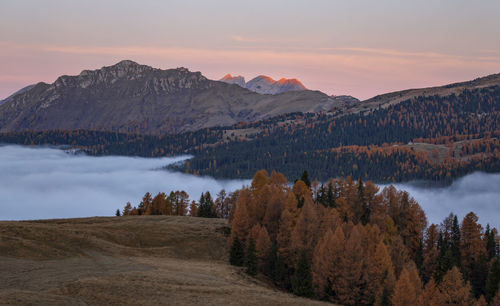 Scenic view of lake by mountains against sky during sunset