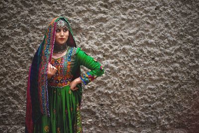 Young woman in traditional clothing standing against wall