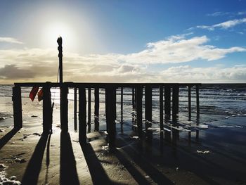 Scenic view of wooden posts in sea against sky