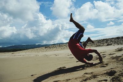 Side view of man skateboarding on beach against sky