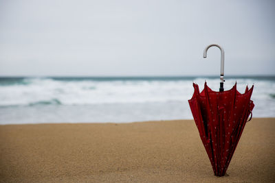 Close-up of red hanging at beach against sky