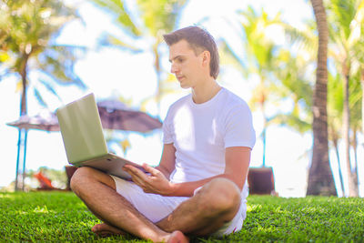 Young man using mobile phone while sitting on grass