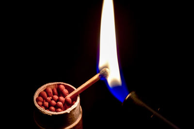 Close-up of igniting matchstick against black background
