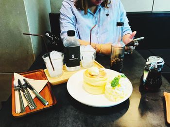 Midsection of woman holding drink served on table