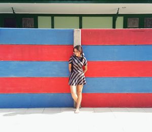 Full length of woman standing against wall