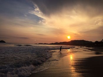 Silhouette person on beach against sky during sunset