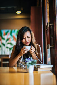 Young woman drinking glass on table