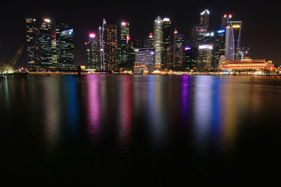 Illuminated buildings by river at night