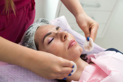 An adult woman is wiped with cotton pad after the carbon peeling procedure in a beauty salon.