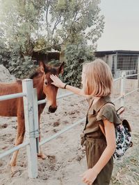 Side view of young woman with horse on field