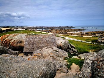 Scenic view of rocks by sea against sky