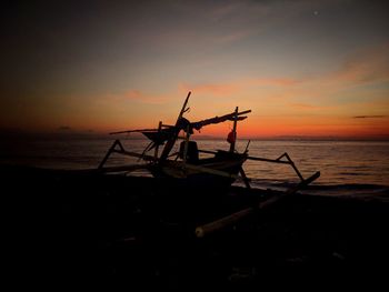 Silhouette fishing boat on sea against sky during sunset