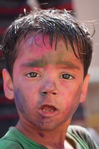 Close-up portrait of boy with powder paint on face during holi