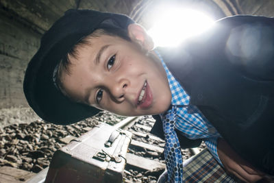 Close-up portrait of cute boy on railroad track in tunnel