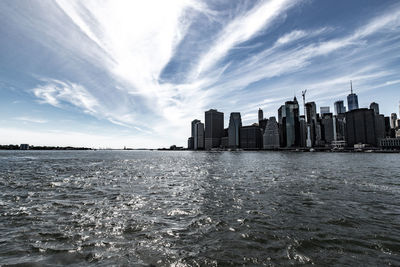 Sea by buildings against sky in city