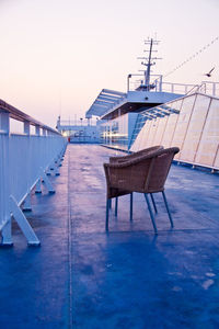 Chairs on deck against clear sky