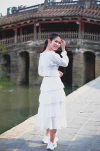 Full length portrait of woman standing against building