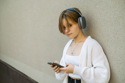 A teenager immerses in tunes, phone in hand, with oversized headphones framing youthful anticipation