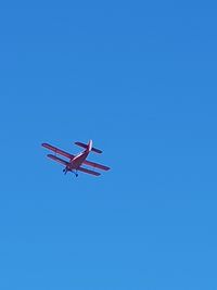 Low angle view of airplane against clear blue sky