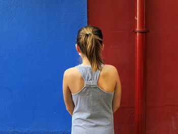 Rear view of woman standing against wall