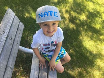 High angle portrait of cute boy sitting on bench in park